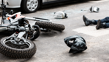 Legs of a person lying on the road after a motorcycle and car accident